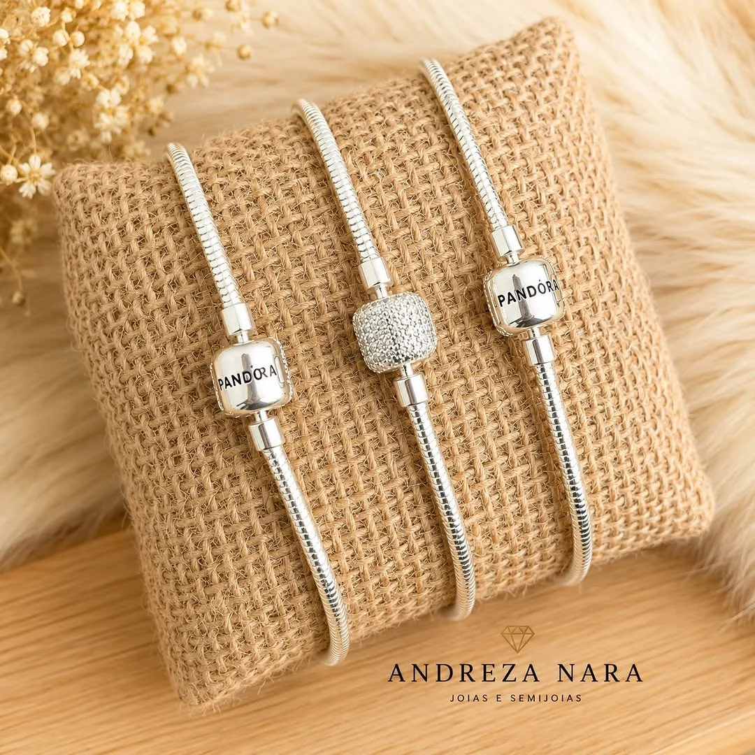 Trio de pulseiras prateadas sobre almofada de linho