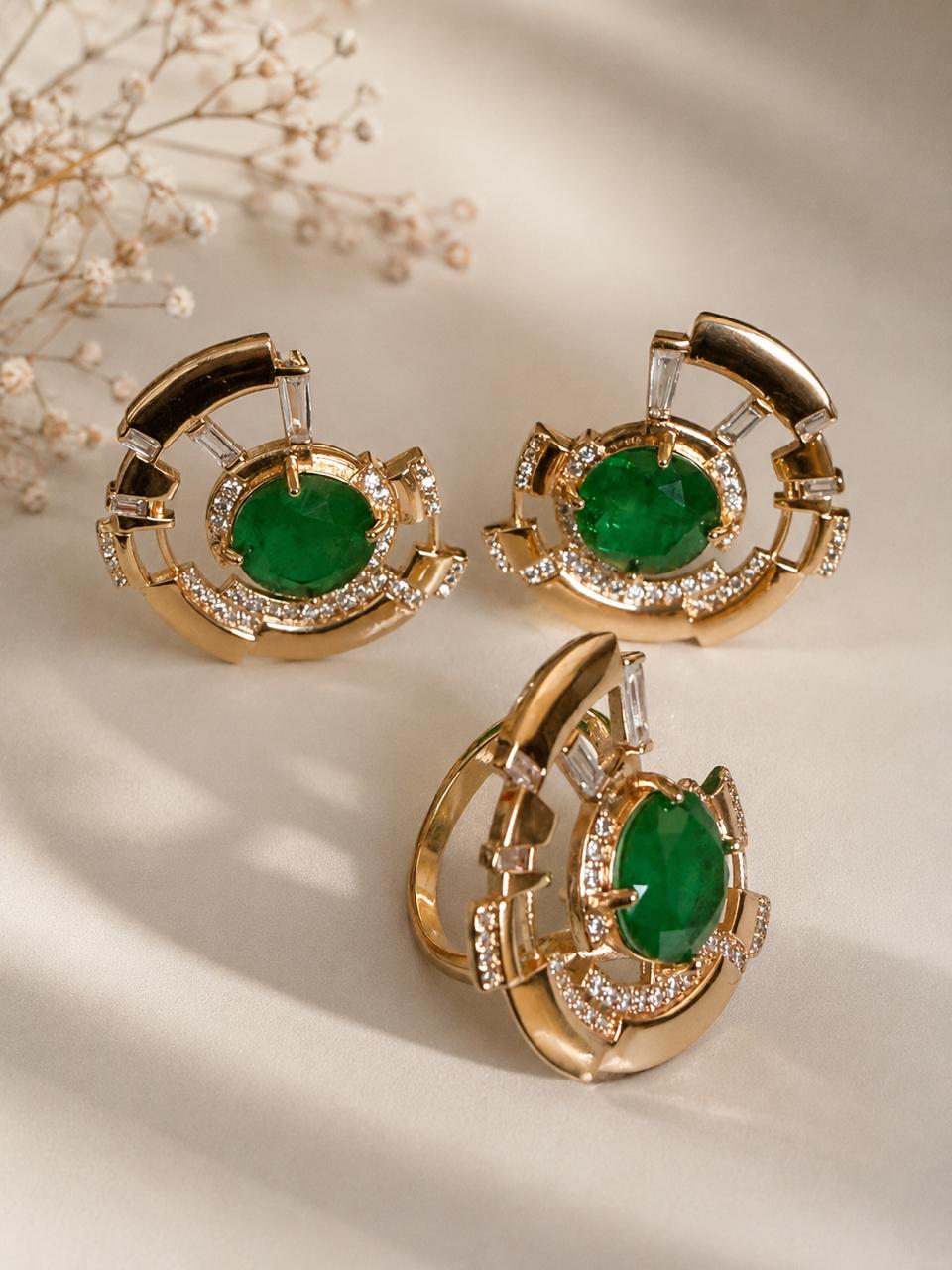 conjunto de brincos e anel com pedras esmeralda e acabamento em dourado.